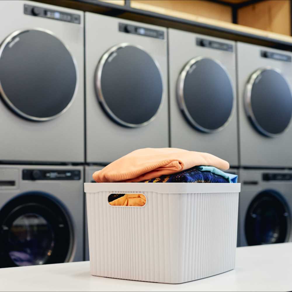 Neatly dried and folded laundry in front of modern dryers in a laundromat